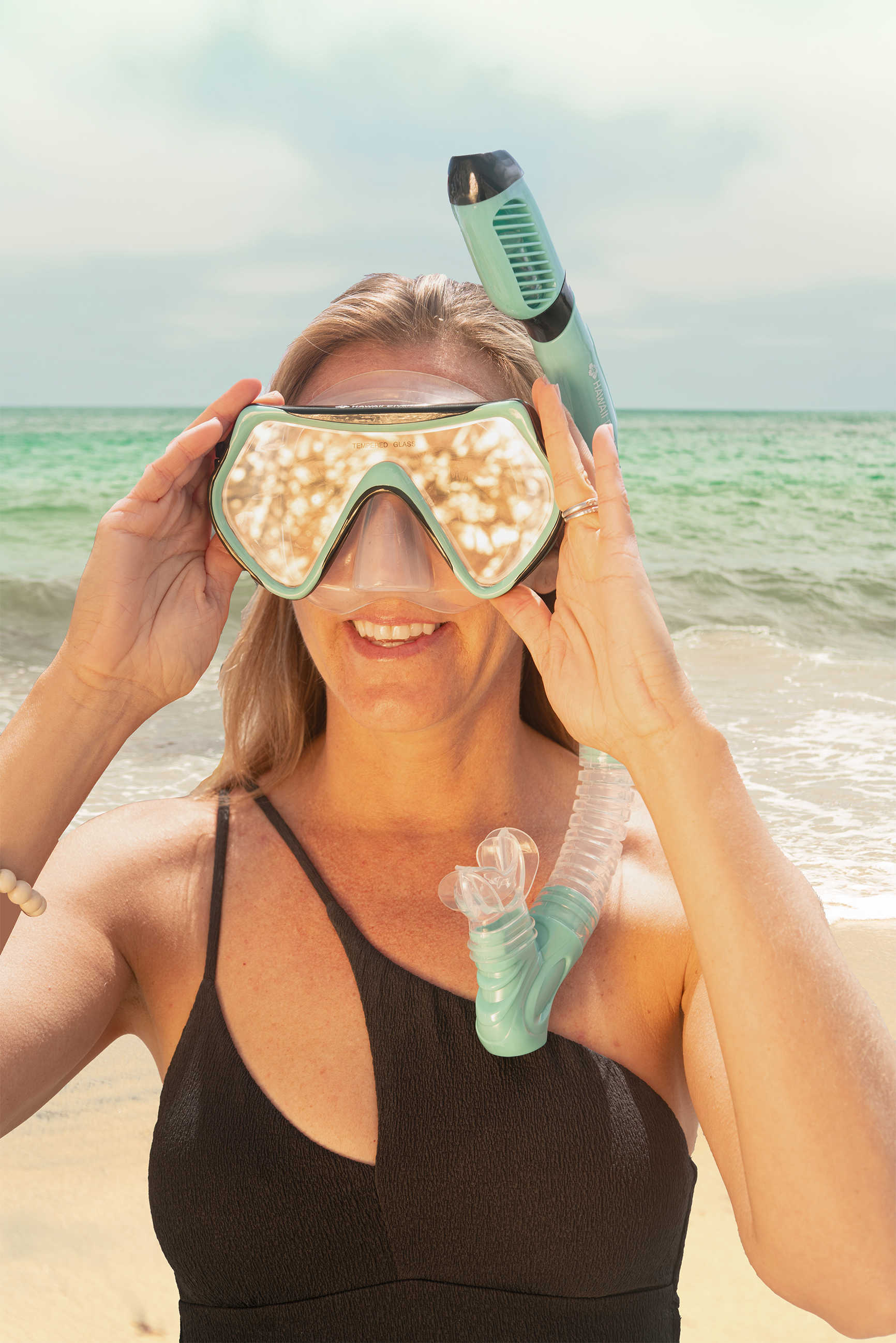 Woman holding a snorkeling mask and snorkel on a beach