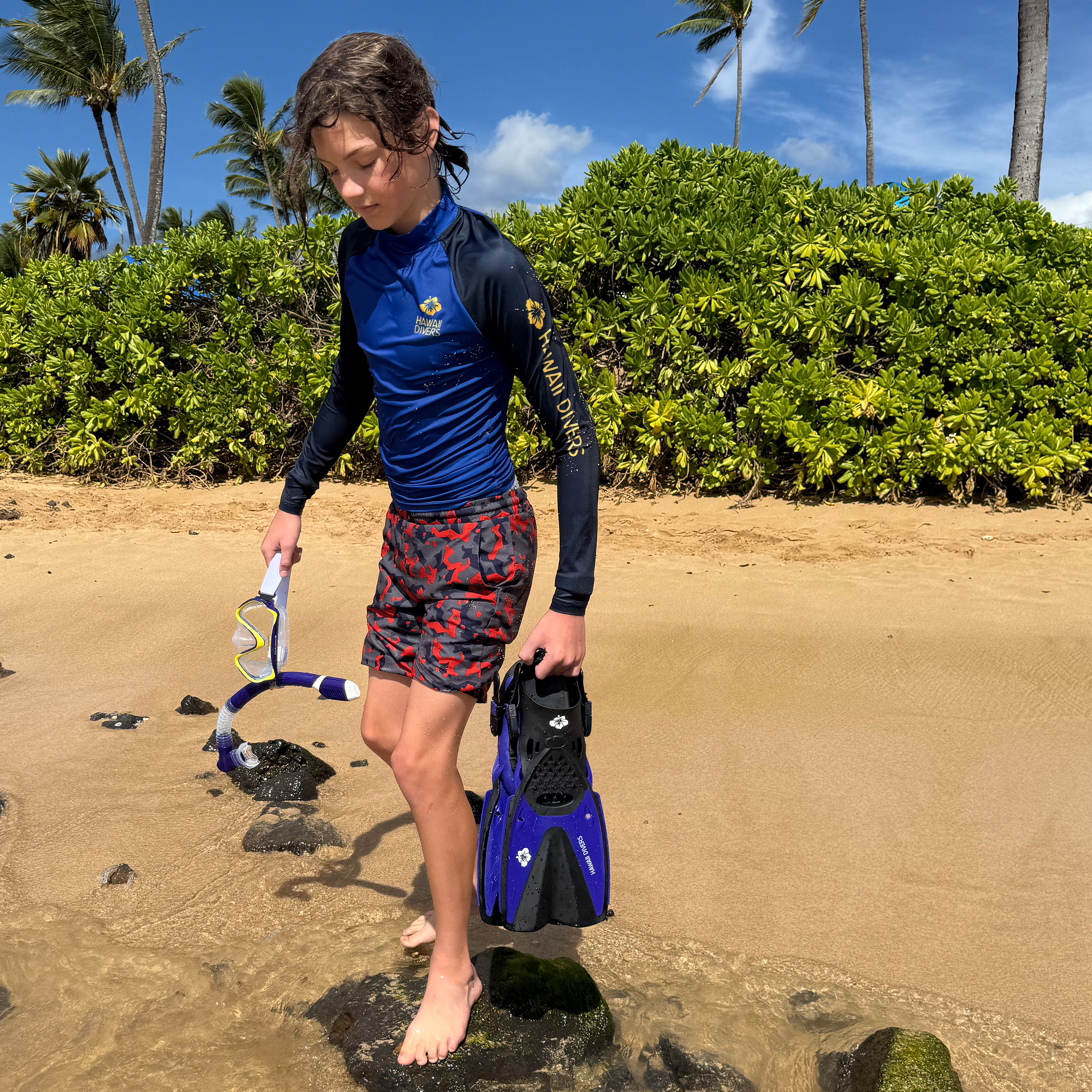 A junior wearing Hawaii Divers gear on the beach